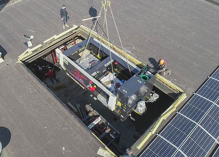 Omdat de plaatlaser op de eerste verdieping bij ERBA moest komen te staan, was er veel voorbereiding nodig. Het dak werd gelift en de laser werd zo’n 50 meter over het gebouw getild met een grote kraanwagen. (Foto: Bureau Sterk Staal)