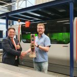 Jan Berends (links) van Bystronic overhandigt de traditionele koebel, die hoort bij de levering van de ByStar Fiber 4020 lasersnijmachine, aan directeur Leon Gijsbers van Vlonder Plaatwerk.