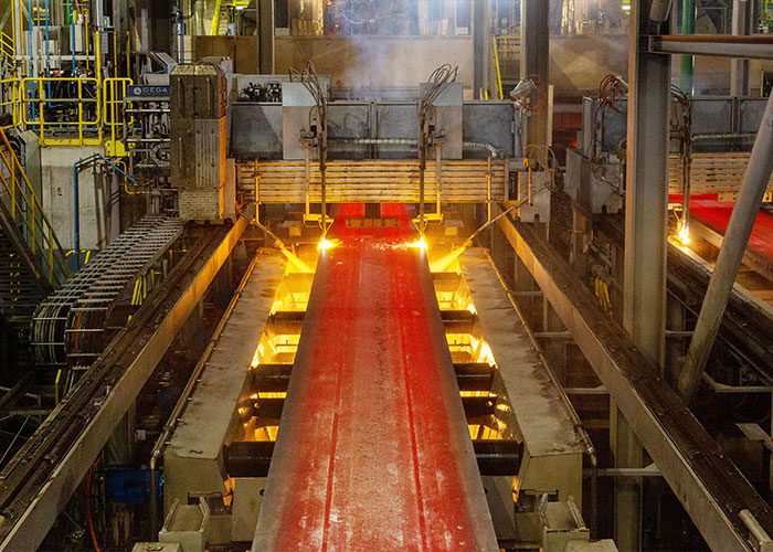 In een continugietmachine wordt vloeibaar staal uitgegoten tot plakken staal, die vervolgens in de Warmbandwalserij tot rollen staal worden uitgewalst.