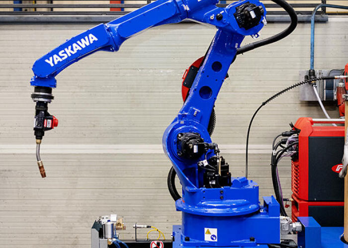 De AR2010 Yaskawa Motoman lasrobot met Fronius TPS400i CMT stroombron die op een meerijdend bordes achter de robot is geplaatst.