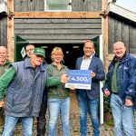 Omringd door deelnemers, neemt Gaby Bossink, Persoonlijk Begeleider bij Stadsboerderij Beeklust, de cheque in ontvangst uit handen van Eelco Osse van Machinefabriek Boessenkool.