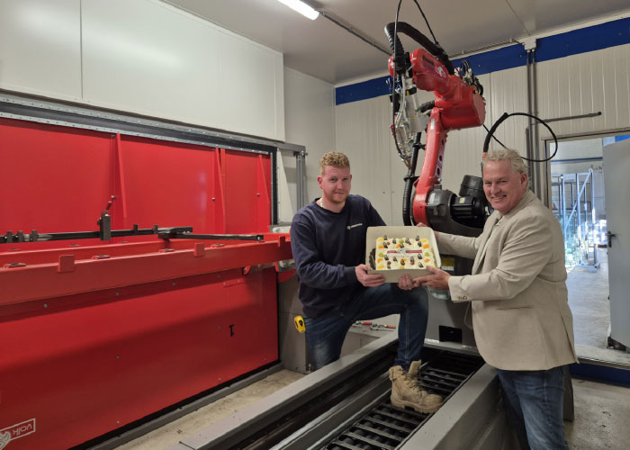 Niels Aalbers, verantwoordelijk voor de operationele zaken bij aalbers|wico, neemt een taart in ontvangst uit handen van technisch adviseur Alex Hol van Valk Welding ter gelegenheid van de ingebruikname van de gerobotiseerde laserlascel. 