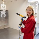 Minister Van Veldhoven hanteert een poedercoatpistool bij de opening van het nieuwe innovatielaboratorium voor poedercoatings van AkzoNobel.